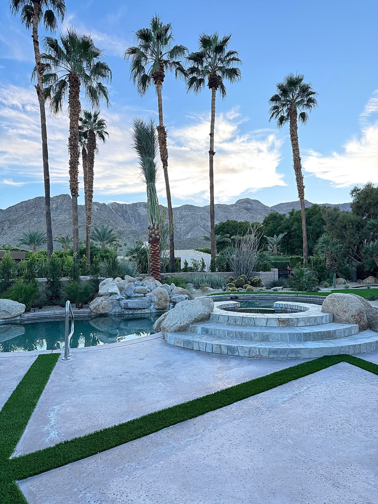 Circular stone spa with raised hearth beside the pool, palms and mountain views