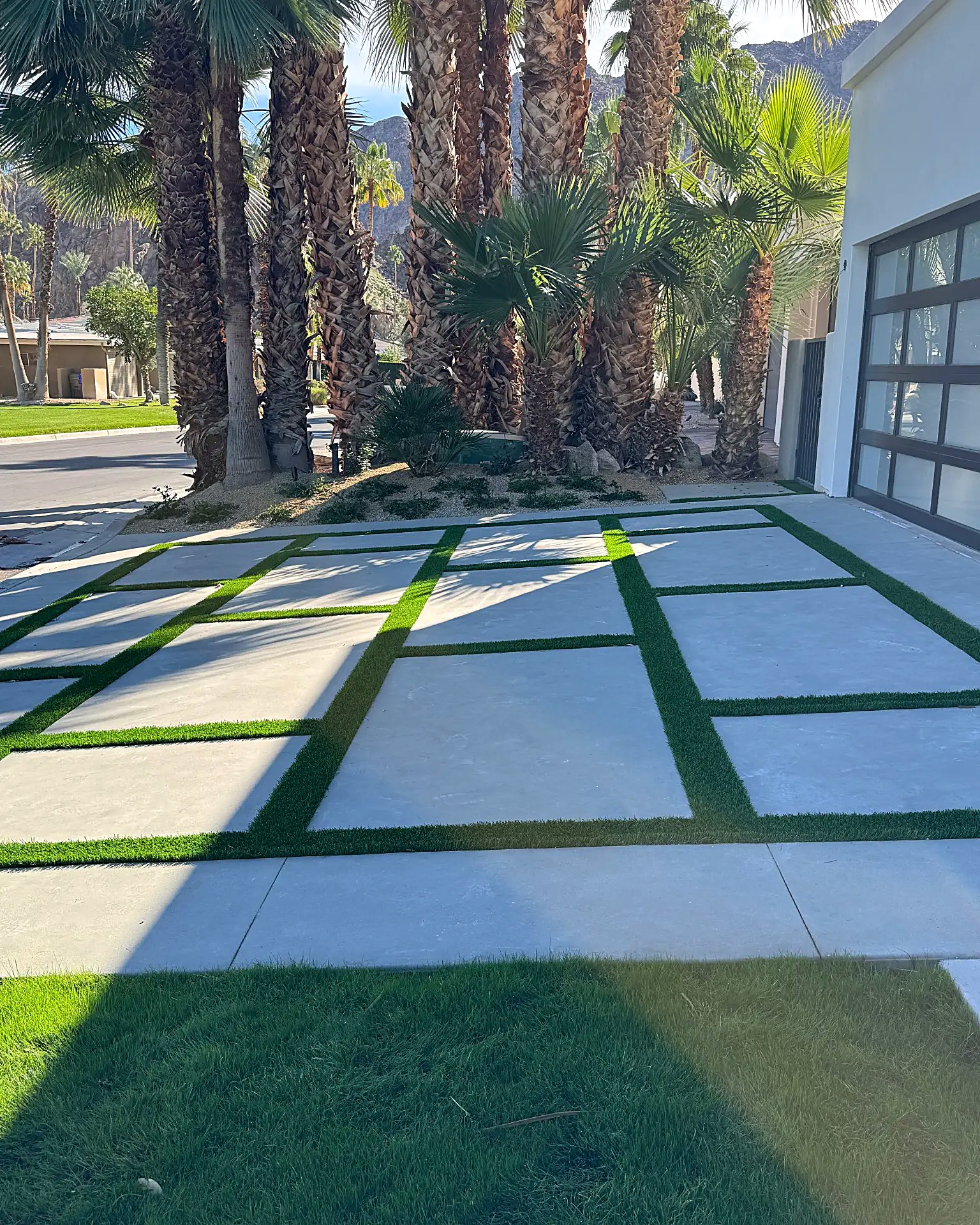 Driveway of large concrete pads set in a grid of artificial turf strips
