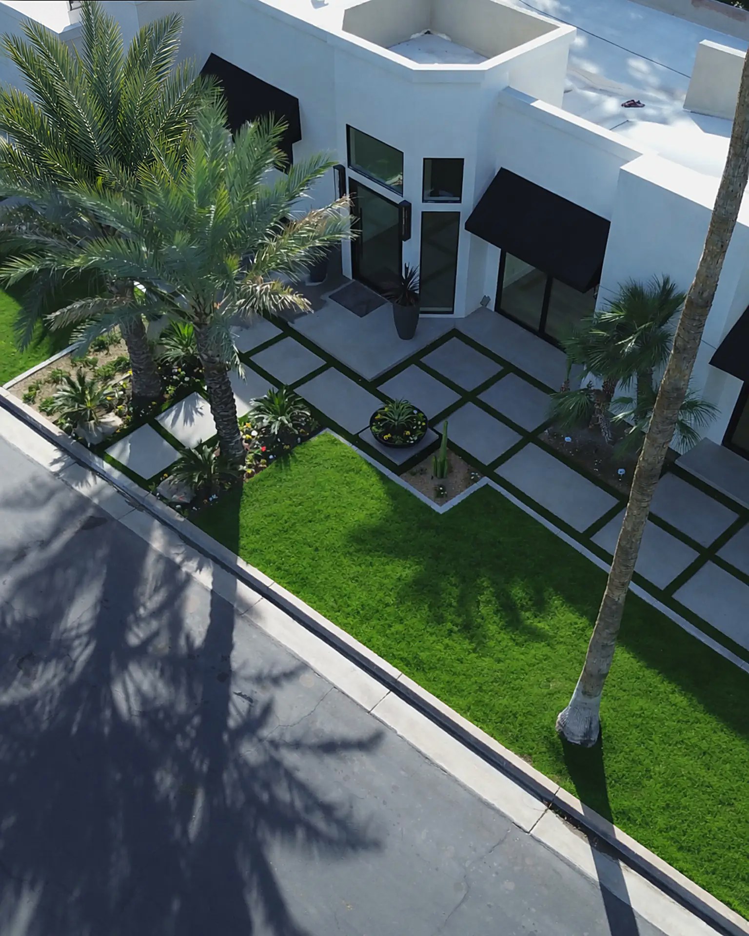 Aerial view of a modern front yard with concrete pads, turf grid and palm trees